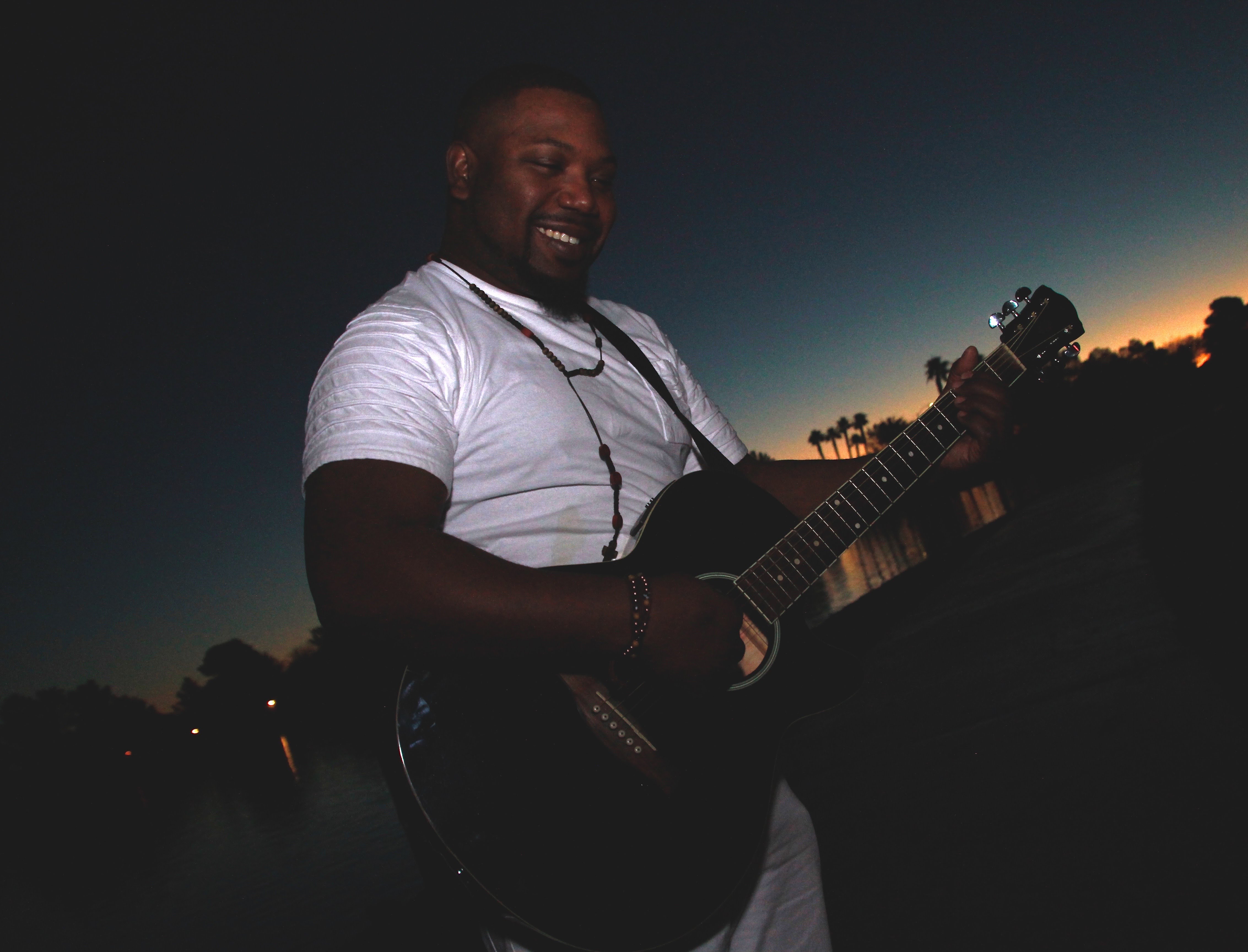 Xavier Jolliff playing acoustic guitar at sunset